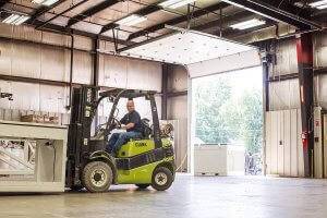 An O'Mara team member operates a forklift to move equipment around in the warehouse.